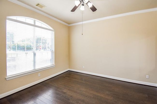 Anchored by a large arched window and smooth wood flooring, this bright space offers flexible use—perfect for a study, guest retreat, or reading lounge—bathed in morning light. | Image 4