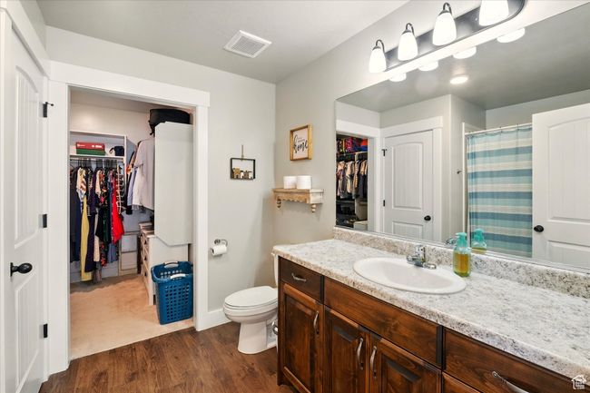 Bathroom featuring a walk in closet, vanity, wood finished floors, and curtained shower | Image 10