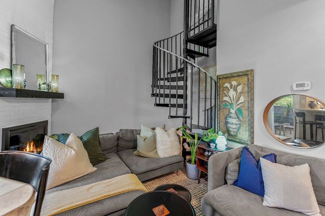 Living area featuring a high ceiling, stairway, and a fireplace | Image 7