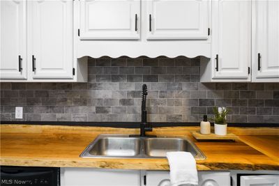 Kitchen with butcher block countertops, sink, decorative backsplash, and white cabinets | Image 3