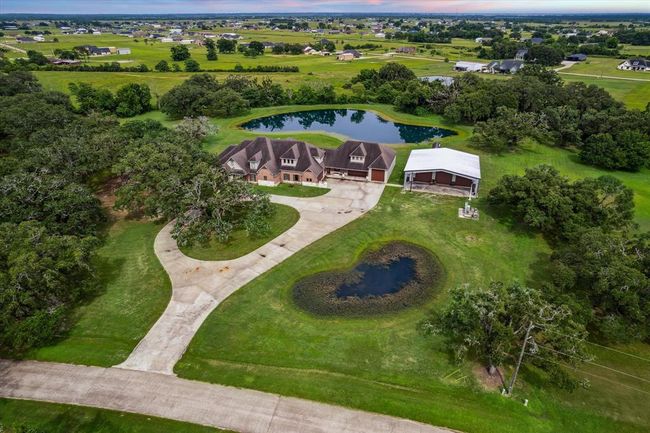 Nestled on 5 acres, this custom two-story home is set against a stunning backdrop of nature. A spacious, circle concrete driveway enhances the home's curb appeal, providing easy access and plenty of room for parking. The expansive lot offers both privacy and endless possibilities for outdoor living. | Image 44