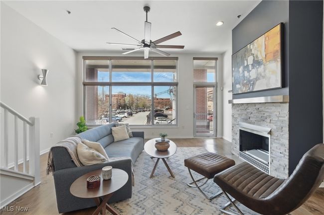 Living area with stairway, wood finished floors, ceiling fan, a fireplace, and baseboards | Image 7