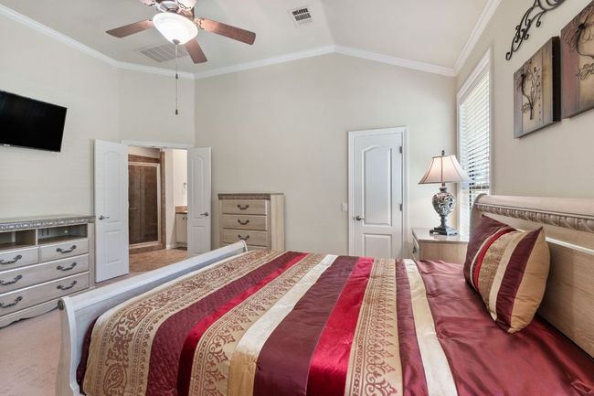 Bedroom with crown molding, lofted ceiling, a ceiling fan, and ensuite bath | Image 24