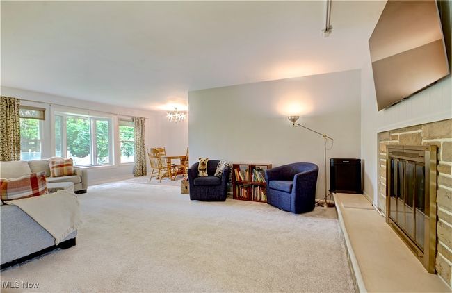Carpeted living area featuring a chandelier and a stone fireplace | Image 6