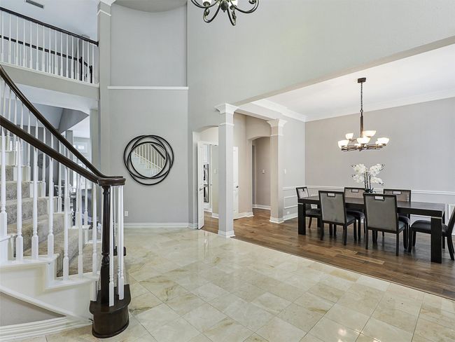Entryway featuring a chandelier, decorative columns, ornamental molding, stairway, and arched walkways | Image 11