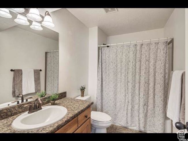 Full bath with vanity, toilet, tile patterned floors, and a shower with shower curtain | Image 11