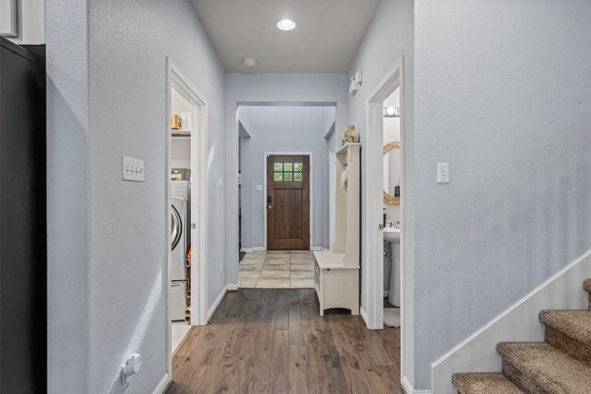 Entrance foyer featuring wood finished floors, stairway, baseboards, and washer / dryer | Image 5