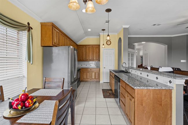 Kitchen with arched walkways, a sink, stainless steel appliances, light tile patterned flooring, and stone countertops | Image 7
