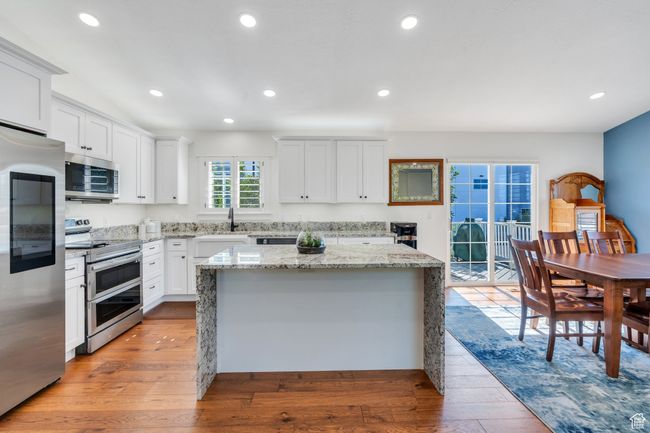Kitchen with appliances with stainless steel finishes, light wood finished floors, a center island, white cabinets, and recessed lighting | Image 5