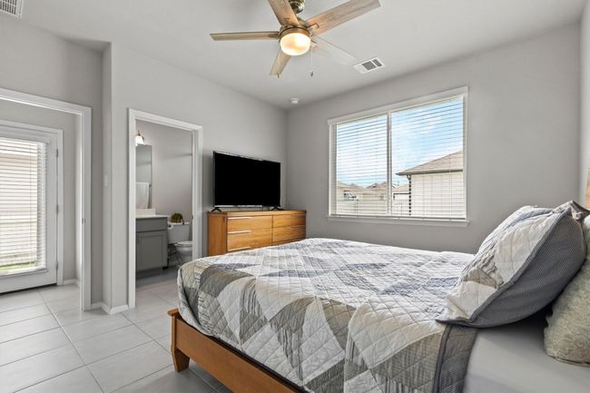 Bedroom with light tile patterned floors, ensuite bathroom, baseboards, and a ceiling fan | Image 9