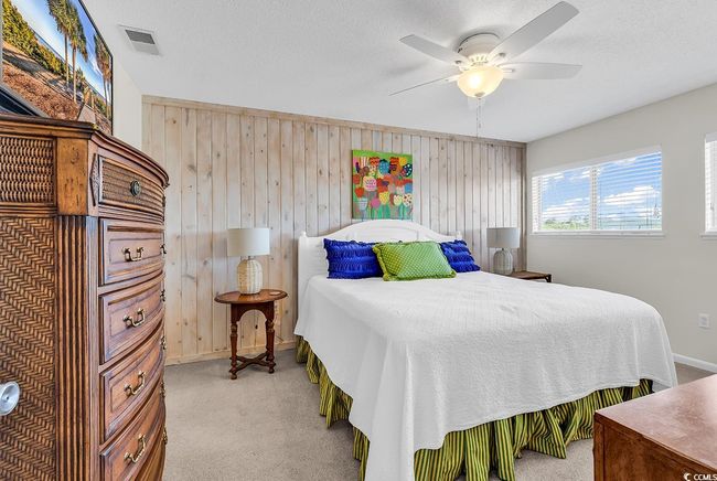 Bedroom with visible vents, wood walls, light carpet, baseboards, and a ceiling fan | Image 19