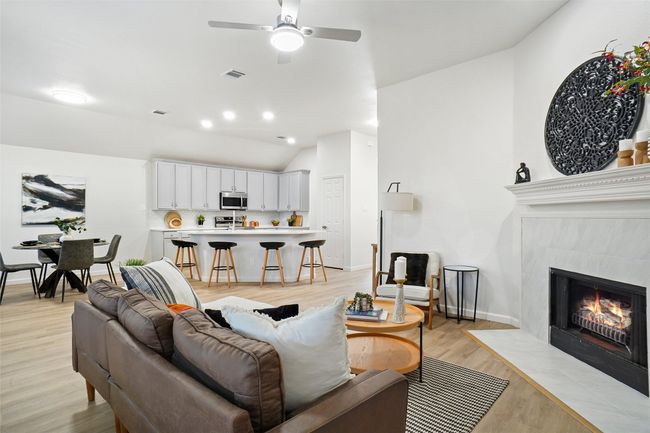 Living room featuring ceiling fan, lofted ceiling, light wood finished floors, a fireplace, and baseboards | Image 4