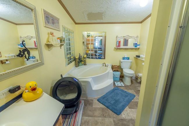 Full bath with a textured ceiling, toilet, a bath, and ornamental molding | Image 11