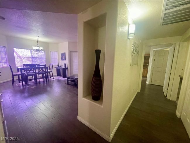 Hall featuring visible vents, baseboards, a notable chandelier, and dark wood-style floors | Image 25