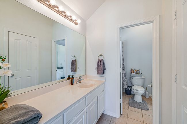 Bathroom featuring vaulted ceiling, vanity with extensive cabinet space, toilet, and tile floors | Image 19