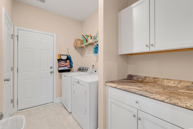 Washroom featuring cabinets, washer and dryer, and light tile patterned floors | Image 32