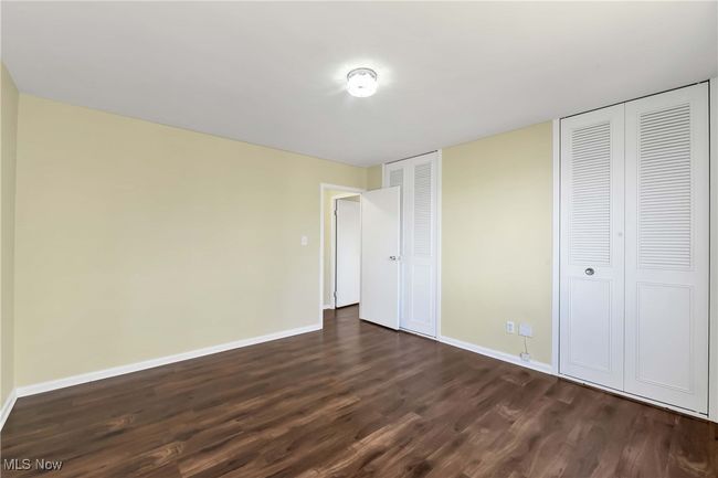 Unfurnished bedroom featuring dark wood finished floors, two closets, and baseboards | Image 17