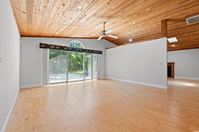 Spare room with wood ceiling, a ceiling fan, lofted ceiling, light wood-style flooring, and a fireplace | Image 5