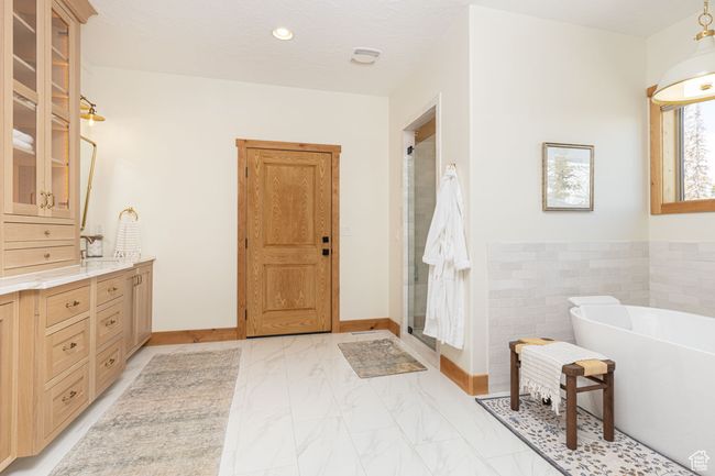 Bathroom with a stall shower, vanity, a soaking tub, marble finish floor, and tile walls | Image 12