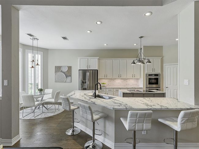 Kitchen with stainless steel appliances, a spacious island, decorative backsplash, recessed lighting, and dark wood-type flooring | Image 19