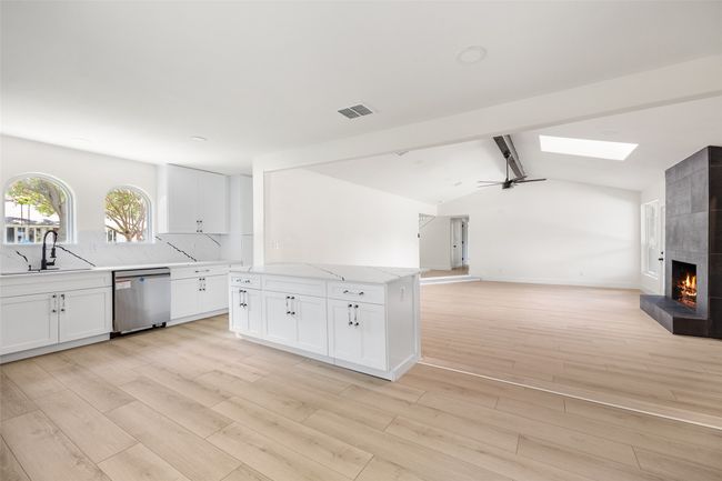 Kitchen featuring a ceiling fan, white cabinets, light stone counters, and light wood-type flooring | Image 8