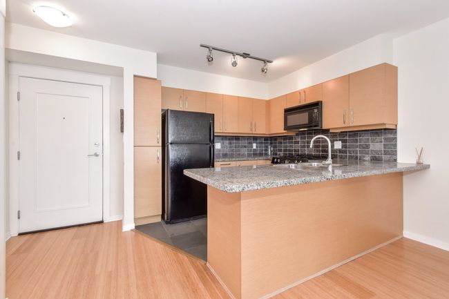 Kitchen featuring black appliances, a peninsula, light wood-type flooring, tasteful backsplash, and rail lighting | Image 7