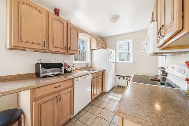 Kitchen featuring radiator, a sink, white appliances, and light tile patterned floors | Image 12