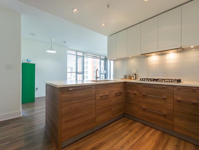 Kitchen featuring brown cabinetry, dark wood-type flooring, extractor fan, white cabinetry, and a peninsula | Image 6