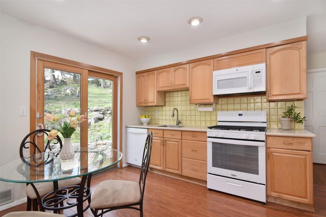 Kitchen featuring light brown cabinets, wood finished floors, white appliances, and light countertops | Image 5