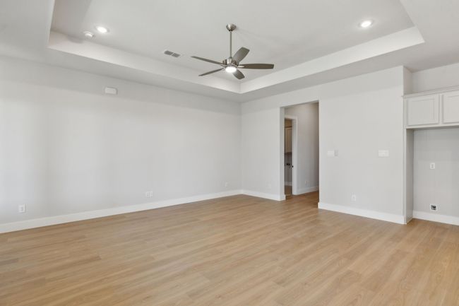Unfurnished room featuring a tray ceiling, ceiling fan, light wood-type flooring, and recessed lighting | Image 12