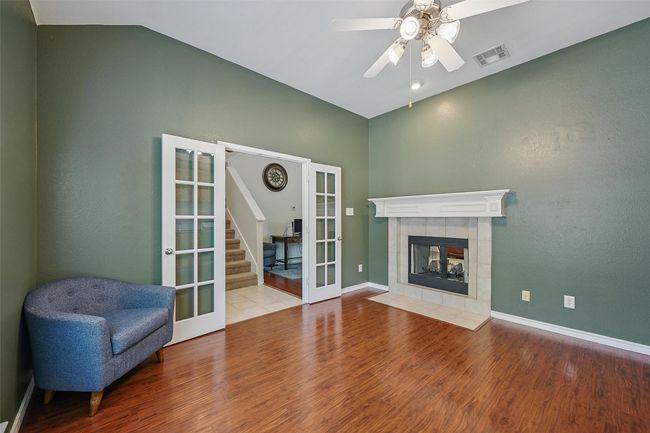 Unfurnished living room featuring french doors, wood finished floors, a ceiling fan, baseboards, and vaulted ceiling | Image 24