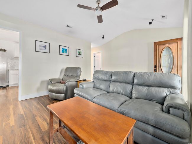 Living room featuring a ceiling fan, vaulted ceiling, wood finished floors, and visible vents | Image 7