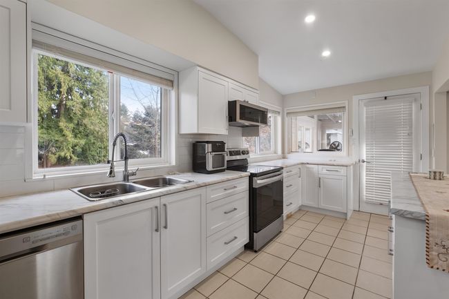 Kitchen featuring backsplash, appliances with stainless steel finishes, white cabinets, and a sink | Image 5