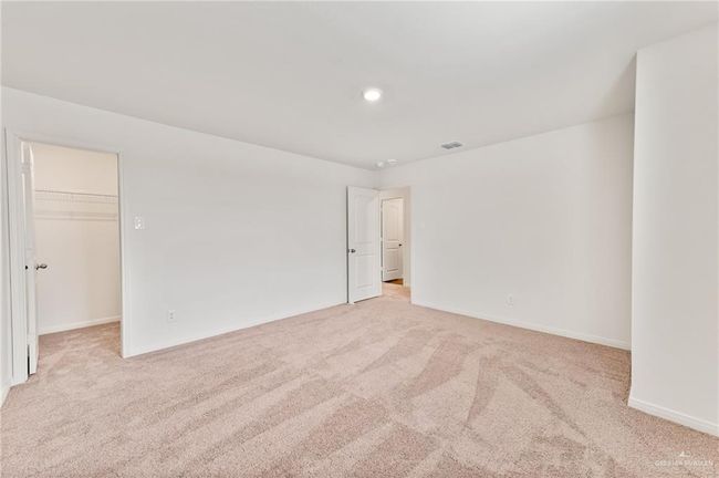 Unfurnished bedroom featuring light carpet, a spacious closet, baseboards, and recessed lighting | Image 18