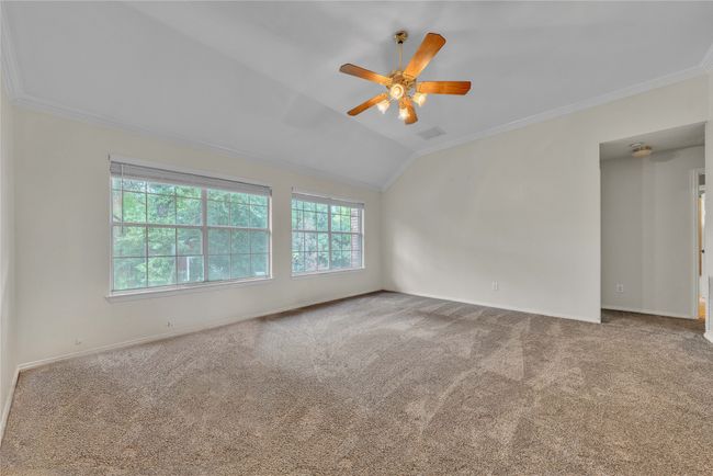 Carpeted spare room featuring ornamental molding, a ceiling fan, and lofted ceiling | Image 24