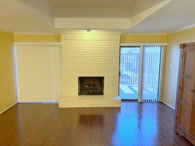 Unfurnished living room with a brick fireplace, dark hardwood / wood-style flooring, a textured ceiling, and crown molding | Image 3