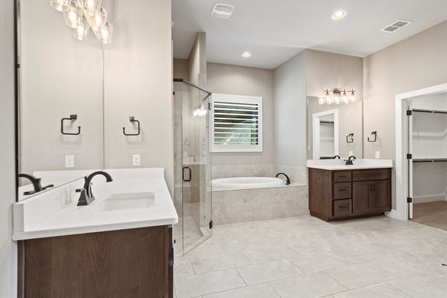 Full bath with a garden tub, a stall shower, two vanities, a walk in closet, and recessed lighting | Image 15