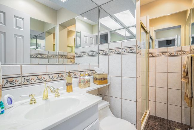 Full bath with a shower stall, toilet, tile walls, and vanity | Image 32