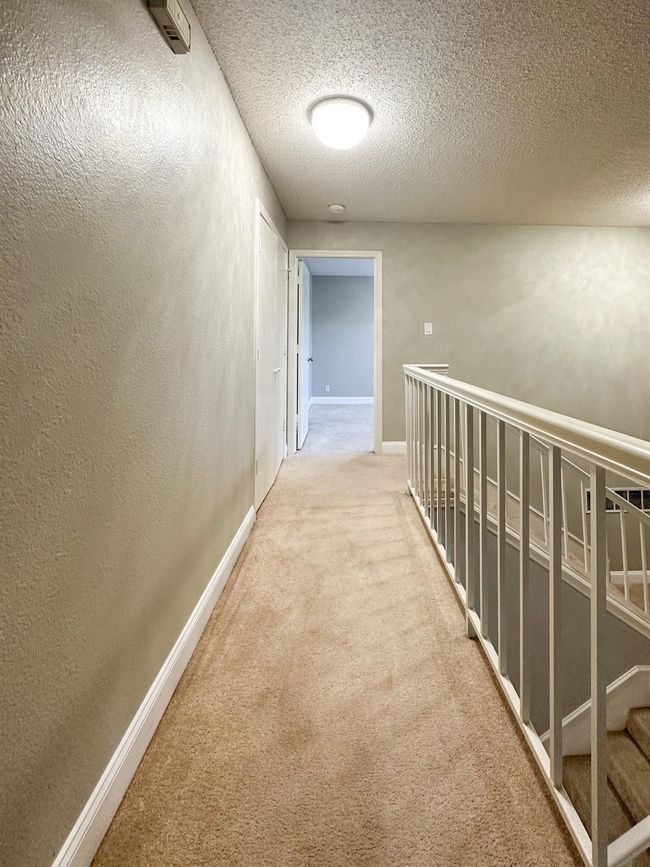 Hall featuring carpet floors, a textured ceiling, and baseboards | Image 11