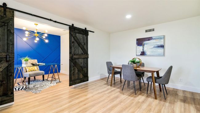 Dining area with a barn door, visible vents, and wood finished floors | Image 16