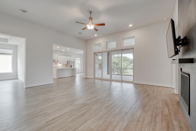 Unfurnished living room featuring a fireplace, a ceiling fan, light wood-style floors, and recessed lighting | Image 8