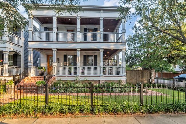 This charming two-story home features a classic Southern design with expansive double porches, a brick walkway, and a manicured front yard enclosed by a black wrought iron fence. Perfect for enjoying outdoor living and entertaining. | Image 4