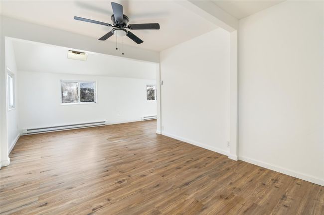 Spare room featuring a wealth of natural light, a baseboard heating unit, and wood finished floors | Image 5