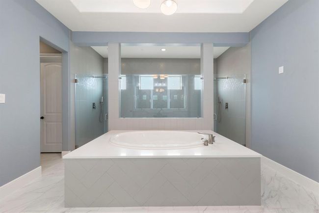 At the heart of this serene spa bath, a luxurious jetted tub is framed by a walk-in shower and elegant herringbone tile—creating a symmetrical sanctuary designed for ultimate relaxation and style. | Image 24