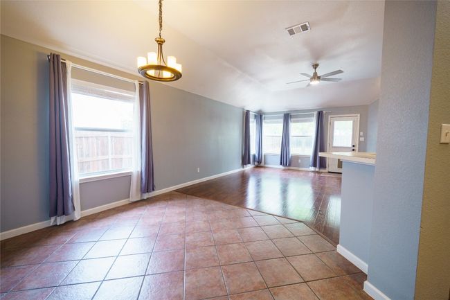 Tiled empty room with ceiling fan, baseboards, and a chandelier | Image 6
