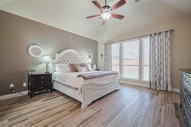 Step into your expansive primary retreat, complete with vaulted ceilings, elegant wood-look tile flooring, and floor-to-ceiling windows that bring in abundant natural light and backyard views. | Image 21
