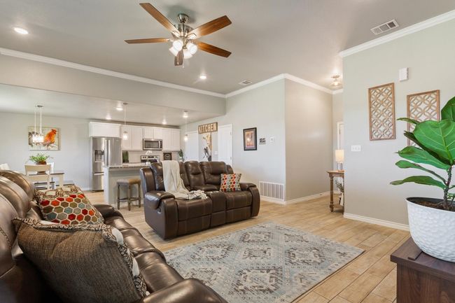 Living area with a ceiling fan, light wood-style floors, crown molding, and recessed lighting | Image 10
