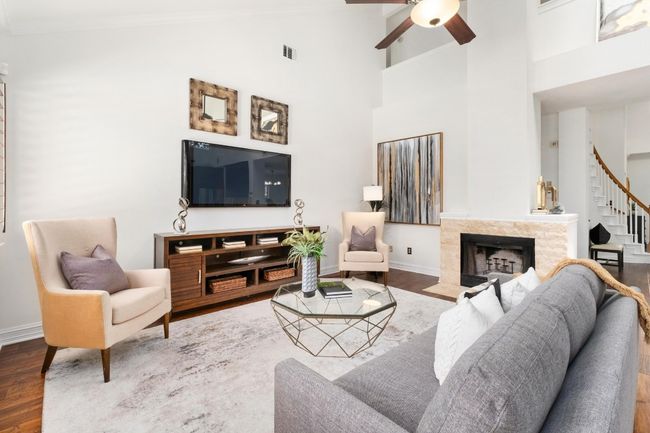 Living area featuring wood finished floors, ornamental molding, stairway, ceiling fan, and a fireplace | Image 8