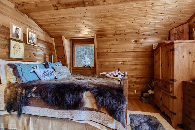 Bedroom featuring lofted ceiling with beams, wooden walls, light wood-style flooring, and wood ceiling | Image 24