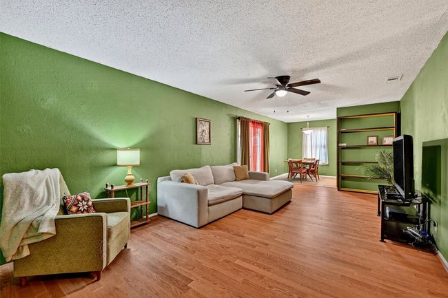 Living area with ceiling fan, wood finished floors, a textured ceiling, and a textured wall | Image 5